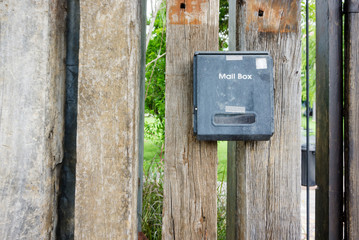 An old mailbox hung on a wooden fence at the entrance to the house.