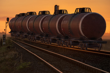 Railway cisterns with fuel standing on the tracks during sunrise