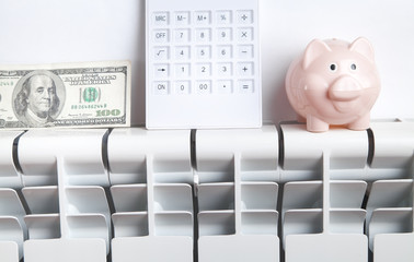 Piggy bank, dollar and calculator on radiator. Energy saving