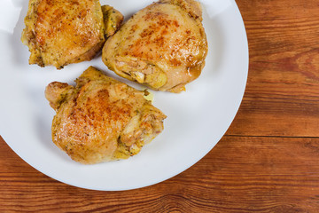 Fried chicken thighs on dish on rustic table, top view