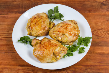 Fried chicken thighs, parsley twigs on dish on rustic table