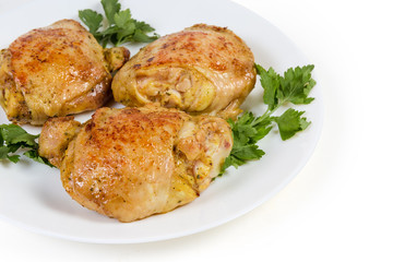 Fried chicken thighs and parsley twigs on dish, fragment closeup