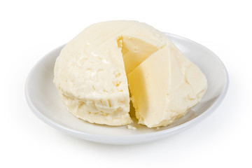 Partly cut ball of soft cheese on saucer close-up