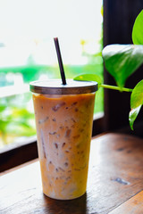 Iced coffee in a tall glass on a wood table with cream  poured over