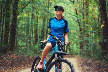 Fototapeta na wymiar Caucasian woman cyclist rides mountain bike forest trails. leisure
