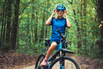 Caucasian woman cyclist rides mountain bike forest trails. leisure