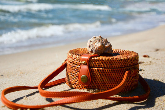 Bally bag with shell on sand beach . Summer concept.