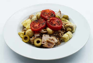Fresh summer salad with: spelled, tomatoe, olive, mushroom and artichoke in white plate. 