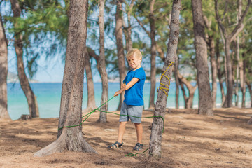 Camping people outdoor lifestyle tourists in summer forest near lazur sea. Blond serious boy in...