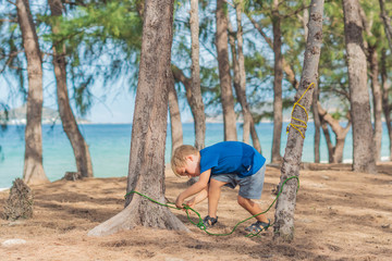 Camping people outdoor lifestyle tourists in summer forest near lazur sea. Blond serious boy in...