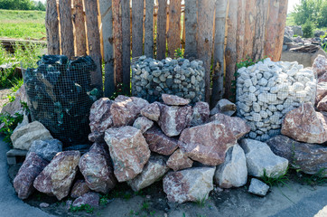 Natural stones for construction on the background of a wooden fence