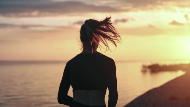 Silhouette of jogger female training at seashore with sea and sky. Shot with RED camera in 4K