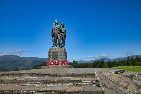 Public Commando Memorial near Spean Bridge, Scottish Highlands. Poppy wreaths at commandos feet. Summer with bright blue sky. Hills in background.