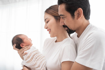 smiling mother and father holding their newborn baby at home..portrait of happy family at home, young parents holding on hands little sweet newborn baby, love and happiness concept.