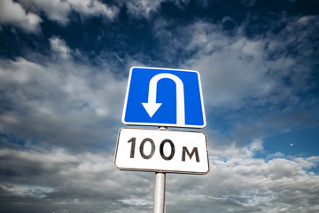 U-turn place road sign on blue sky with clouds. Wrong turn