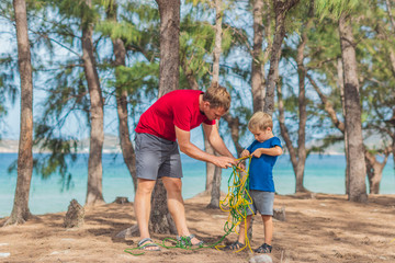 Camping people outdoor lifestyle tourists in summer forest near lazur sea. Blond boy son with...