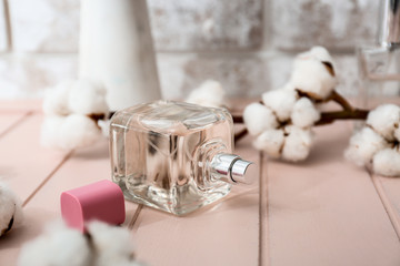 Bottle of perfume and cotton branch on table