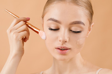 Beautiful young woman with foundation on her face against color background