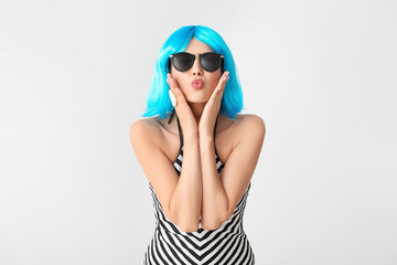 Beautiful young woman in wig on light background