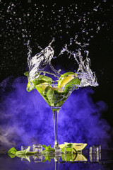 Glass of fresh mojito with splash on dark background