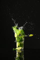 Glass of fresh mojito with splash on dark background