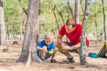 Camping people outdoor lifestyle tourists in summer forest near lazur sea. Blond boy son with...