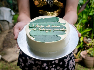 Girlfriend handing over a small cake with green icing and a heartwarming message. Tagalog words...