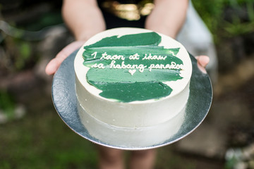 Girlfriend handing over a small cake with green icing and a heartwarming message. Tagalog words...