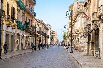 Fototapeta na wymiar Italy, Reggio di Calabria, May 11, 2018: Pedestrian tourist street Corso Giuseppe Garibaldi with old traditional typical buildings, lamps and green trees in historical centre of the city