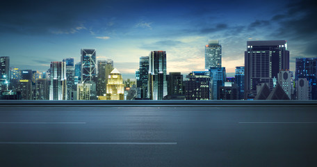 Empty asphalt road and cityscape skyline at night