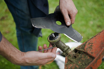 hands replacing a garden trimmer blade