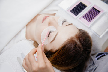 Eyelash extension procedure. Woman master combs lashes fake