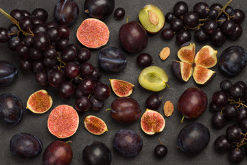 Still life of fruits. Bunch of grapes. Figs and plums. Cut figs, plum halves, plum pits.