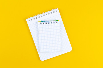 Open notebook on bright yellow paper background. School accessory with copy space on color background. The concept of studying or planning. Flat lay.