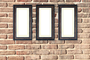 Fototapeta na wymiar Three empty picture frames on old brick wall