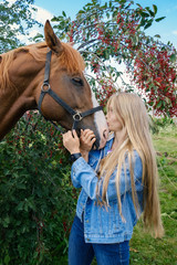 A young blonde woman kisses her horse