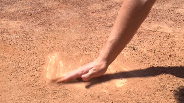Wiping Dirt of Home Plate With Hand