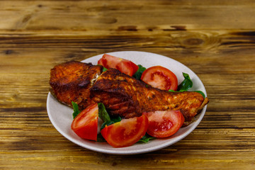Grilled salmon fillet with spinach and tomatoes on wooden table