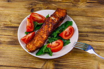 Grilled salmon fillet with spinach and tomatoes on wooden table