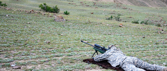 Sniper is preparing for accurate shooting using a long-range sighting system.