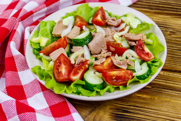 Tasty tuna salad with lettuce and fresh vegetables on wooden table