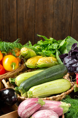 Assortment of vegetables in a wooden box on the table. A lot of different raw vegetables in the basket. Zucchini, radish, eggplant, corn, garlic, pepper and eggplant on the table. Healthy food concept