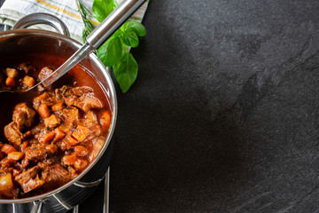 Italian pork stew on dark background with copy space