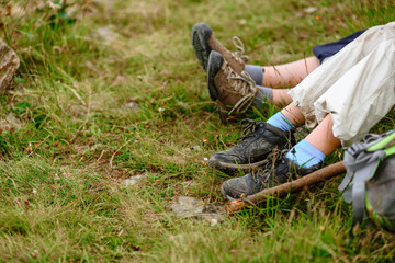 Closeup of kid's legs resting on green grass after hiking in Carpathians