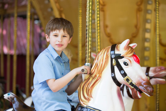 Boy riding a retro carousel in the form of a horse