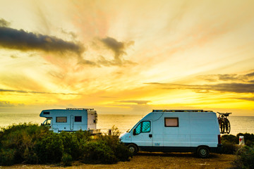 Camper vehicles on beach at sunrise