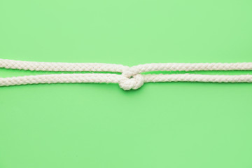 Rope with knot on color background