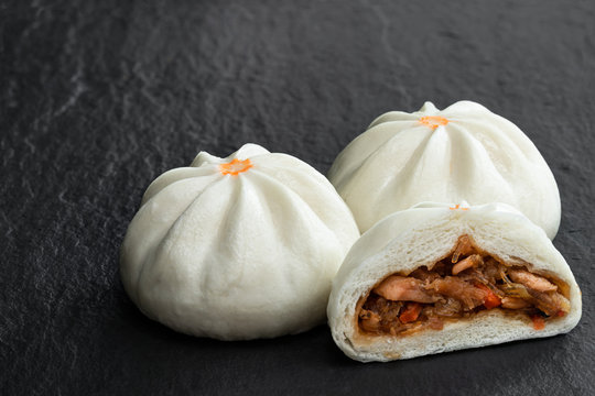 Steamed bao buns with delicious filling on black stone background