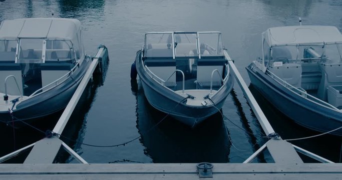Small private leisure motor boats docked at port or marina on lake or river. Cinematic shot of engine yachts or boats on winter parking. Expensive luxurious marina for expensive sailing hobby