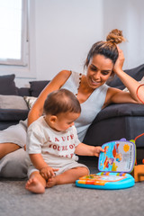 Young Caucasian mother with her son sitting on the floor next to the black sofa. Teleworking and caring for your child, a new normal after the coronavirus pandemic, covid-19. Watching the child play